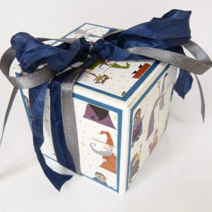 handdekorierte Geschenkschachtel mit Zaubermeister-Motiv, Zaubermeister Schachtel mit blauem Band, Detailansicht Zaubermeister Illustration, Geschenkbox mit Sternenmuster und Zaubermeister, Schachtel geöffnet mit Geschenkinhalt, kreative Geschenkverpackung mit Zauberer, handgemachte Zaubermeister Box auf grauem Hintergrund