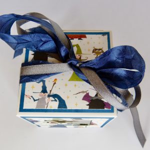 handdekorierte Geschenkschachtel mit Zaubermeister-Motiv, Zaubermeister Schachtel mit blauem Band, Detailansicht Zaubermeister Illustration, Geschenkbox mit Sternenmuster und Zaubermeister, Schachtel geöffnet mit Geschenkinhalt, kreative Geschenkverpackung mit Zauberer, handgemachte Zaubermeister Box auf grauem Hintergrund