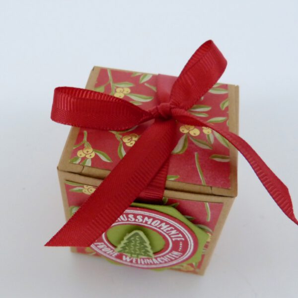 handdekorierte geschenkschachtel mit stern und schriftzug, geschenkbox mit weihnachtlichem band und etikett, detailaufnahme stern auf geschenkschachtel, geschenkschachtel von oben mit schleife, seitenansicht handdekorierte weihnachtsschachtel, geschenkschachtel mit karomuster und band, weihnachtliche geschenkverpackung mit lecker-lecker motiv