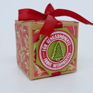 handdekorierte geschenkschachtel mit stern und schriftzug, geschenkbox mit weihnachtlichem band und etikett, detailaufnahme stern auf geschenkschachtel, geschenkschachtel von oben mit schleife, seitenansicht handdekorierte weihnachtsschachtel, geschenkschachtel mit karomuster und band, weihnachtliche geschenkverpackung mit lecker-lecker motiv