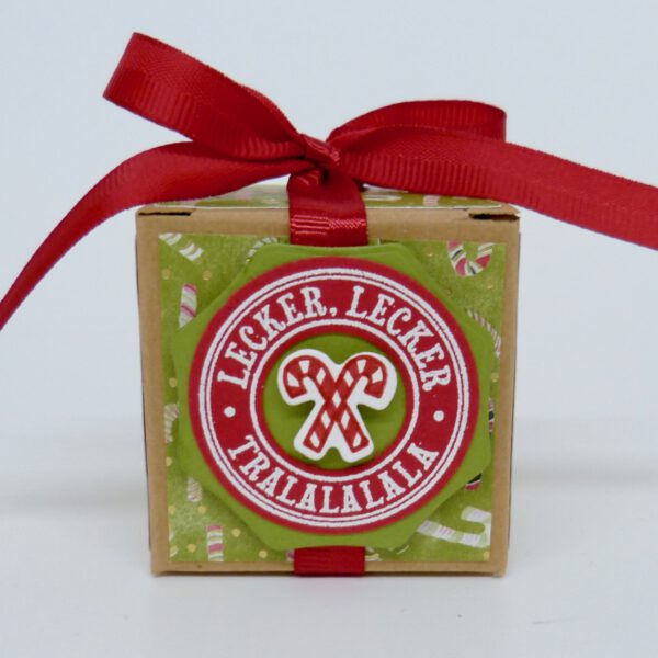 Lecker Lecker, handdekorierte geschenkschachtel mit stern und schriftzug, geschenkbox mit weihnachtlichem band und etikett, detailaufnahme stern auf geschenkschachtel, geschenkschachtel von oben mit schleife, seitenansicht handdekorierte weihnachtsschachtel, geschenkschachtel mit karomuster und band, weihnachtliche geschenkverpackung mit lecker-lecker motiv