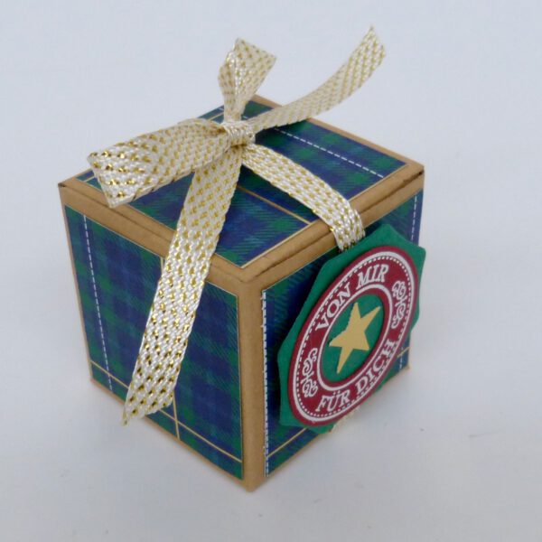handdekorierte geschenkschachtel mit stern und schriftzug, geschenkbox mit weihnachtlichem band und etikett, detailaufnahme stern auf geschenkschachtel, geschenkschachtel von oben mit schleife, seitenansicht handdekorierte weihnachtsschachtel, geschenkschachtel mit karomuster und band, weihnachtliche geschenkverpackung mit lecker-lecker motiv