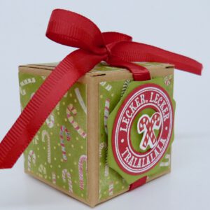 Lecker Lecker, handdekorierte geschenkschachtel mit stern und schriftzug, geschenkbox mit weihnachtlichem band und etikett, detailaufnahme stern auf geschenkschachtel, geschenkschachtel von oben mit schleife, seitenansicht handdekorierte weihnachtsschachtel, geschenkschachtel mit karomuster und band, weihnachtliche geschenkverpackung mit lecker-lecker motiv
