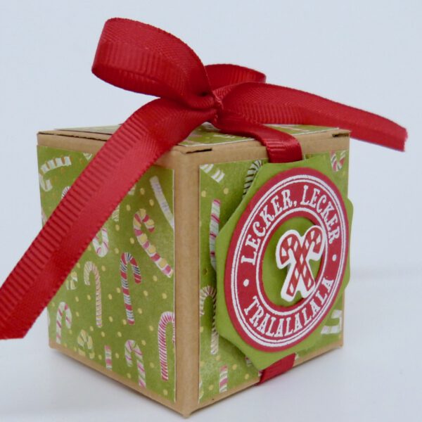 Lecker Lecker, handdekorierte geschenkschachtel mit stern und schriftzug, geschenkbox mit weihnachtlichem band und etikett, detailaufnahme stern auf geschenkschachtel, geschenkschachtel von oben mit schleife, seitenansicht handdekorierte weihnachtsschachtel, geschenkschachtel mit karomuster und band, weihnachtliche geschenkverpackung mit lecker-lecker motiv