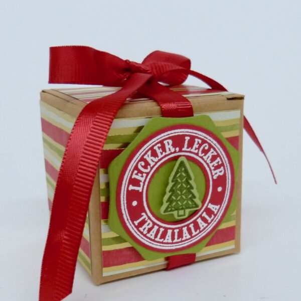 Tralalalala, handdekorierte geschenkschachtel mit stern und schriftzug, geschenkbox mit weihnachtlichem band und etikett, detailaufnahme stern auf geschenkschachtel, geschenkschachtel von oben mit schleife, seitenansicht handdekorierte weihnachtsschachtel, geschenkschachtel mit karomuster und band, weihnachtliche geschenkverpackung mit lecker-lecker motiv