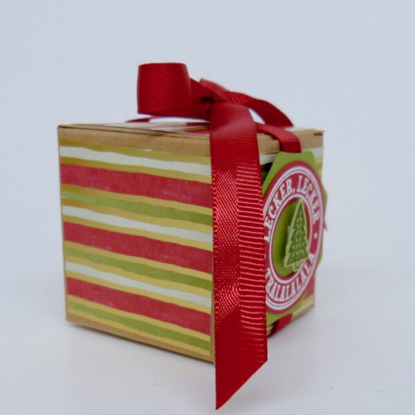 handdekorierte geschenkschachtel mit stern und schriftzug, geschenkbox mit weihnachtlichem band und etikett, detailaufnahme stern auf geschenkschachtel, geschenkschachtel von oben mit schleife, seitenansicht handdekorierte weihnachtsschachtel, geschenkschachtel mit karomuster und band, weihnachtliche geschenkverpackung mit lecker-lecker motiv