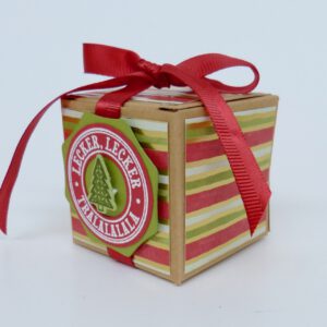 handdekorierte geschenkschachtel mit stern und schriftzug, geschenkbox mit weihnachtlichem band und etikett, detailaufnahme stern auf geschenkschachtel, geschenkschachtel von oben mit schleife, seitenansicht handdekorierte weihnachtsschachtel, geschenkschachtel mit karomuster und band, weihnachtliche geschenkverpackung mit lecker-lecker motiv