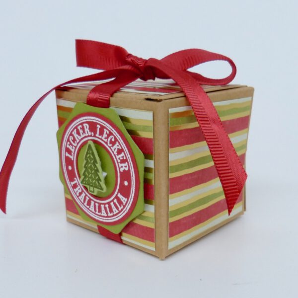handdekorierte geschenkschachtel mit stern und schriftzug, geschenkbox mit weihnachtlichem band und etikett, detailaufnahme stern auf geschenkschachtel, geschenkschachtel von oben mit schleife, seitenansicht handdekorierte weihnachtsschachtel, geschenkschachtel mit karomuster und band, weihnachtliche geschenkverpackung mit lecker-lecker motiv