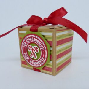 Genussmomente, handdekorierte geschenkschachtel mit stern und schriftzug, geschenkbox mit weihnachtlichem band und etikett, detailaufnahme stern auf geschenkschachtel, geschenkschachtel von oben mit schleife, seitenansicht handdekorierte weihnachtsschachtel, geschenkschachtel mit karomuster und band, weihnachtliche geschenkverpackung mit lecker-lecker motiv