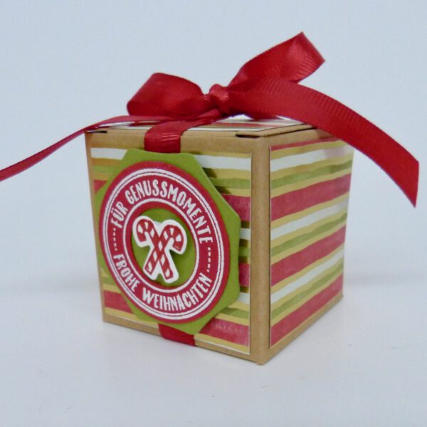 Genussmomente, handdekorierte geschenkschachtel mit stern und schriftzug, geschenkbox mit weihnachtlichem band und etikett, detailaufnahme stern auf geschenkschachtel, geschenkschachtel von oben mit schleife, seitenansicht handdekorierte weihnachtsschachtel, geschenkschachtel mit karomuster und band, weihnachtliche geschenkverpackung mit lecker-lecker motiv