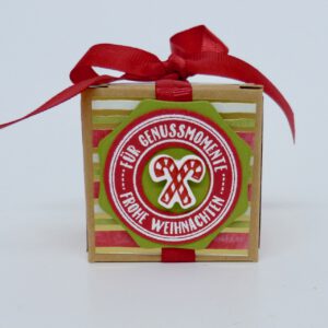 Genussmomente, handdekorierte geschenkschachtel mit stern und schriftzug, geschenkbox mit weihnachtlichem band und etikett, detailaufnahme stern auf geschenkschachtel, geschenkschachtel von oben mit schleife, seitenansicht handdekorierte weihnachtsschachtel, geschenkschachtel mit karomuster und band, weihnachtliche geschenkverpackung mit lecker-lecker motiv
