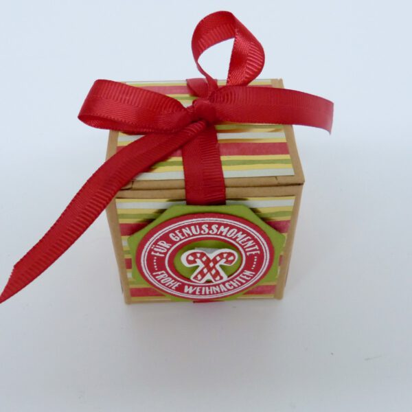 handdekorierte geschenkschachtel mit stern und schriftzug, geschenkbox mit weihnachtlichem band und etikett, detailaufnahme stern auf geschenkschachtel, geschenkschachtel von oben mit schleife, seitenansicht handdekorierte weihnachtsschachtel, geschenkschachtel mit karomuster und band, weihnachtliche geschenkverpackung mit lecker-lecker motiv