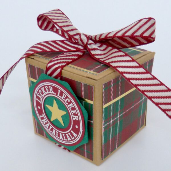 handdekorierte geschenkschachtel mit stern und schriftzug, geschenkbox mit weihnachtlichem band und etikett, detailaufnahme stern auf geschenkschachtel, geschenkschachtel von oben mit schleife, seitenansicht handdekorierte weihnachtsschachtel, geschenkschachtel mit karomuster und band, weihnachtliche geschenkverpackung mit lecker-lecker motiv