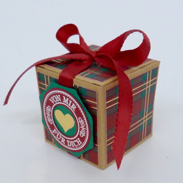 handdekorierte geschenkschachtel mit stern und schriftzug, geschenkbox mit weihnachtlichem band und etikett, detailaufnahme stern auf geschenkschachtel, geschenkschachtel von oben mit schleife, seitenansicht handdekorierte weihnachtsschachtel, geschenkschachtel mit karomuster und band, weihnachtliche geschenkverpackung mit lecker-lecker motiv