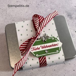 Geschenkdose Frohe Weihnachten mit Schneeflocken, Geschenkdose mit Schleifenband und Anhänger, Detailansicht Schneeflocken-Metallaccessoire, offene Geschenkdose mit Inhalt, Nahaufnahme Banderole Geschenkdose, Geschenkdose als Geschenkverpackung, handgemachte Weihnachtsdose mit Etikett