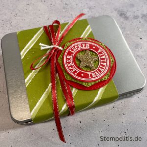 Geschenkdose Frohe Weihnachten mit Schneeflocken, Geschenkdose mit Schleifenband und Anhänger, Detailansicht Schneeflocken-Metallaccessoire, offene Geschenkdose mit Inhalt, Nahaufnahme Banderole Geschenkdose, Geschenkdose als Geschenkverpackung, handgemachte Weihnachtsdose mit Etikett