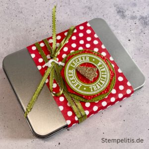 Geschenkdose Frohe Weihnachten mit Schneeflocken, Geschenkdose mit Schleifenband und Anhänger, Detailansicht Schneeflocken-Metallaccessoire, offene Geschenkdose mit Inhalt, Nahaufnahme Banderole Geschenkdose, Geschenkdose als Geschenkverpackung, handgemachte Weihnachtsdose mit Etikett
