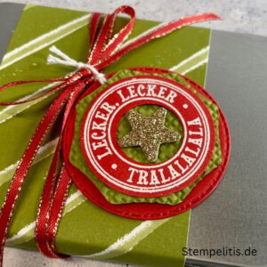 Geschenkdose Frohe Weihnachten mit Schneeflocken, Geschenkdose mit Schleifenband und Anhänger, Detailansicht Schneeflocken-Metallaccessoire, offene Geschenkdose mit Inhalt, Nahaufnahme Banderole Geschenkdose, Geschenkdose als Geschenkverpackung, handgemachte Weihnachtsdose mit Etikett