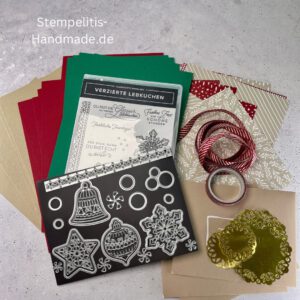 Bastelmaterialien für weihnachtliche Karten oder Projekte. Zu sehen sind grünes und rotes Tonpapier, gemustertes Designerpapier, ein Stempelset namens „Verzierte Lebkuchen“ mit passenden deutschen Sprüchen, metallische Stanzformen für Weihnachtsmotive (Stern, Glocke, Schneeflocke, Kugel), rote und weiße Kordel, goldene Zierdeckchen sowie Briefumschläge