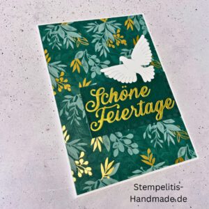 Handgemachte Weihnachtskarte mit Taube, Detailfoto Deko auf Weihnachtskarte, Nahaufnahme edler Schriftzug Frohe Weihnachten, Übersicht handgemachte Weihnachtskarte mit Umschlag, Detail handgemachte Schneeflocke mit Glitzer, Arrangement Weihnachtskarte mit grüner Hintergrundfarbe, Close-up auf Weihnachtskarte