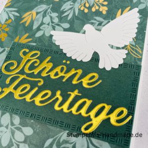 Handgemachte Weihnachtskarte mit Taube, Detailfoto Deko auf Weihnachtskarte, Nahaufnahme edler Schriftzug Frohe Weihnachten, Übersicht handgemachte Weihnachtskarte mit Umschlag, Detail handgemachte Schneeflocke mit Glitzer, Arrangement Weihnachtskarte mit grüner Hintergrundfarbe, Close-up auf Weihnachtskarte