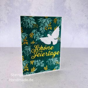 Handgemachte Weihnachtskarte mit Taube, Detailfoto Deko auf Weihnachtskarte, Nahaufnahme edler Schriftzug Frohe Weihnachten, Übersicht handgemachte Weihnachtskarte mit Umschlag, Detail handgemachte Schneeflocke mit Glitzer, Arrangement Weihnachtskarte mit grüner Hintergrundfarbe, Close-up auf Weihnachtskarte