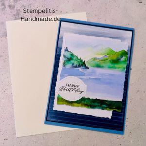 Handgemachte Geburtstagskarte mit Aquarell Landschaft, Detailansicht der Karte mit grünem See, Nahaufnahme vom handgemalten Motiv, Karte auf hellem Betonhintergrund präsentiert, Künstlerische Karte mit Berge und Wasserfarbe, Glückwunschkarte offen und geschlossen, Rückseite der Geburtstagskarte mit Platz für eigenen Text
