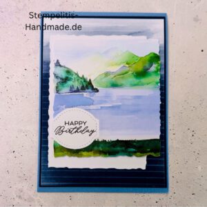 Handgemachte Geburtstagskarte mit Aquarell Landschaft, Detailansicht der Karte mit grünem See, Nahaufnahme vom handgemalten Motiv, Karte auf hellem Betonhintergrund präsentiert, Künstlerische Karte mit Berge und Wasserfarbe, Glückwunschkarte offen und geschlossen, Rückseite der Geburtstagskarte mit Platz für eigenen Text