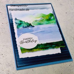 Handgemachte Geburtstagskarte mit Aquarell Landschaft, Detailansicht der Karte mit grünem See, Nahaufnahme vom handgemalten Motiv, Karte auf hellem Betonhintergrund präsentiert, Künstlerische Karte mit Berge und Wasserfarbe, Glückwunschkarte offen und geschlossen, Rückseite der Geburtstagskarte mit Platz für eigenen Text