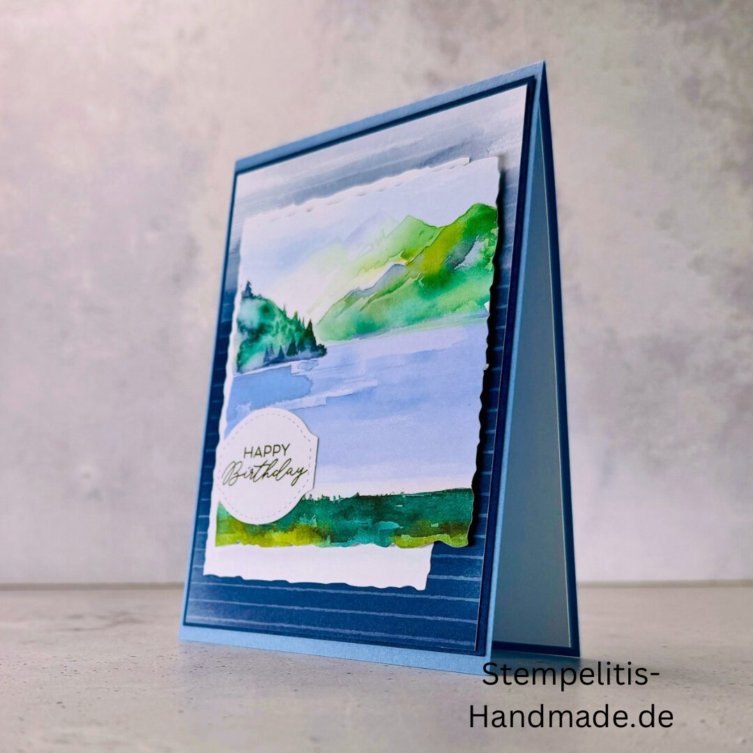 Handgemachte Geburtstagskarte mit Aquarell Landschaft, Detailansicht der Karte mit grünem See, Nahaufnahme vom handgemalten Motiv, Karte auf hellem Betonhintergrund präsentiert, Künstlerische Karte mit Berge und Wasserfarbe, Glückwunschkarte offen und geschlossen, Rückseite der Geburtstagskarte mit Platz für eigenen Text