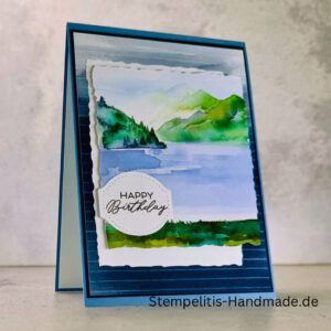 Handgemachte Geburtstagskarte mit Aquarell Landschaft, Detailansicht der Karte mit grünem See, Nahaufnahme vom handgemalten Motiv, Karte auf hellem Betonhintergrund präsentiert, Künstlerische Karte mit Berge und Wasserfarbe, Glückwunschkarte offen und geschlossen, Rückseite der Geburtstagskarte mit Platz für eigenen Text