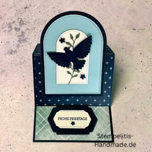 Aufstellkarte Frohe Feiertage handgemacht, Weihnachtskarte mit ausgestanzter Taube, dekorative Aufstellkarte hellblau und dunkelblau, Weihnachtsgrußkarte mit floralem Motiv, Detailaufnahme handgefertigte Weihnachtskarte, festliche Karte zum Aufstellen, elegante Frohe Feiertage Grußkarte