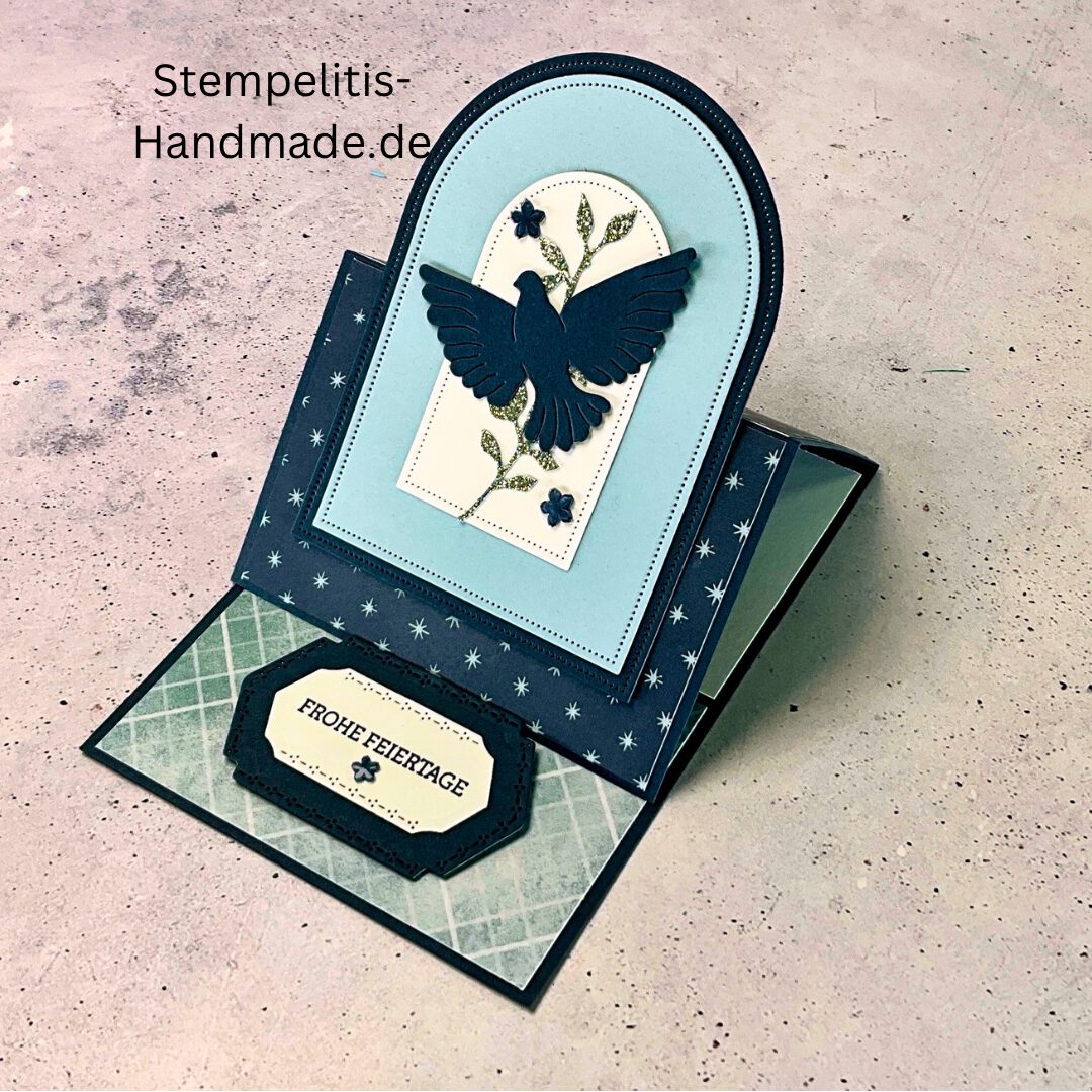 Aufstellkarte Frohe Feiertage handgemacht, Weihnachtskarte mit ausgestanzter Taube, dekorative Aufstellkarte hellblau und dunkelblau, Weihnachtsgrußkarte mit floralem Motiv, Detailaufnahme handgefertigte Weihnachtskarte, festliche Karte zum Aufstellen, elegante Frohe Feiertage Grußkarte