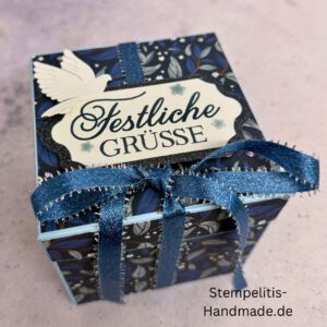 Explosionsbox in Blau mit weißer Taube, Geöffnete Explosionsbox von oben mit Geschenk und Sternenmuster, Nahaufnahme vom Deckel mit Schriftzug Festliche Grüße, Detailansicht Taube auf blauem Hintergrund, Nahaufnahme der Box innen mit Etikett, Geschenkbox im Weihnachtsdesign mit Schleife, Handgemachte Explosionsbox im festlichen Look