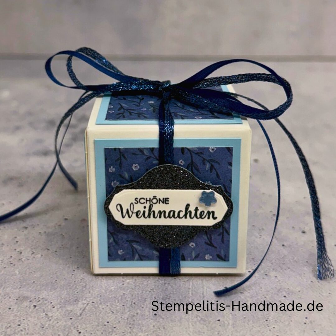 Explosionsbox in Blau mit weißer Taube, Geöffnete Explosionsbox von oben mit Geschenk und Sternenmuster, Nahaufnahme vom Deckel mit Schriftzug Festliche Grüße, Detailansicht Taube auf blauem Hintergrund, Nahaufnahme der Box innen mit Etikett, Geschenkbox im Weihnachtsdesign mit Schleife, Handgemachte Explosionsbox im festlichen Look
