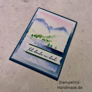 Handgemachte Karte Ich denke an dich mit Aquarell-Landschaft, Detailansicht Schriftzug Ich denke an dich auf Grußkarte, Aquarellkarte mit Bergen und Tannen als Motiv, Nahaufnahme handgemalte Grußkarte Ich denke an dich, Landschaftsaquarell auf handgemachter Karte Ich denke an dich, Geschenkidee: handgemachte Karte Ich denke an dich in Blau, Karte Ich denke an dich mit Umschlag