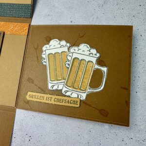 Grillmeister Aufklappkarte mit Biermotiv in maskulinem Design, handgemacht und hochwertig gestaltet Detailansicht der Grillmeister Aufklappkarte mit Bier und Grillmotiv, stilvolle handgefertigte Männerkarte Geöffnete Grillmeister Aufklappkarte mit Bier, Innenbereich mit Platz für persönliche Worte Handgemachte Grillmeister Karte mit Biermotiv auf neutralem Hintergrund fotografiert Grillmeister Aufklappkarte als Geschenkidee für Männer, hochwertig und humorvoll gestaltet Nahaufnahme der Papierstruktur und Details der handgemachten Grillmeister Aufklappkarte Grillmeister Karte mit Bier und Grillmotiv als stilvolle Aufmerksamkeit für Männer Aufklappkarte für Grillfans mit Biermotiv, elegant und mit liebevollen Details gestaltet